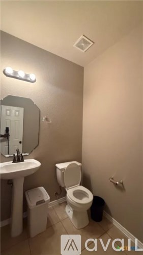 A bathroom with a toilet, sink, and mirror.