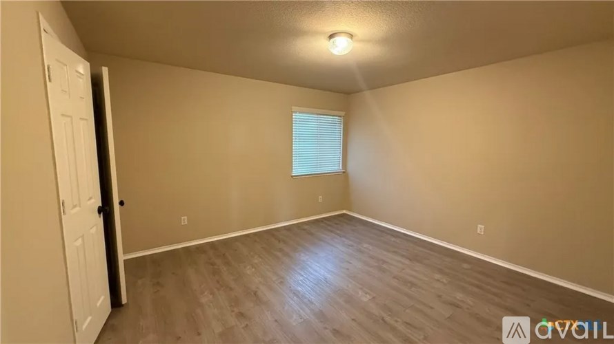 A room with a door, window, and wooden floor.