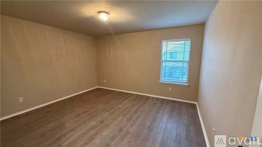 A room with wooden flooring and a window with blinds.