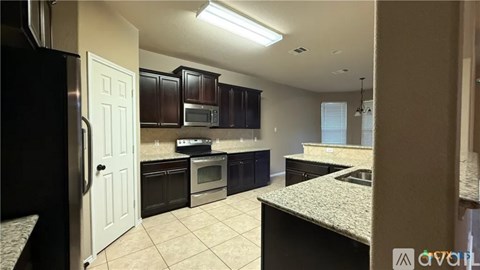 A kitchen with a black refrigerator and a white door.