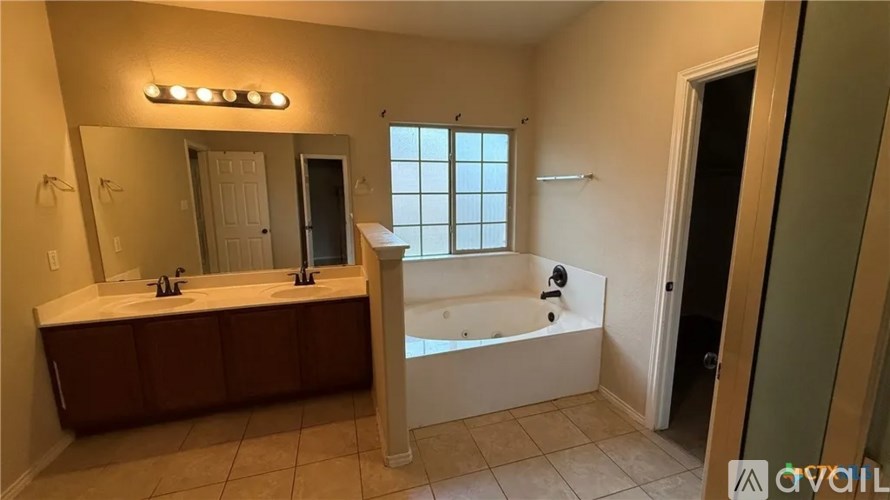 A bathroom with a large mirror, double sinks, and a bathtub.