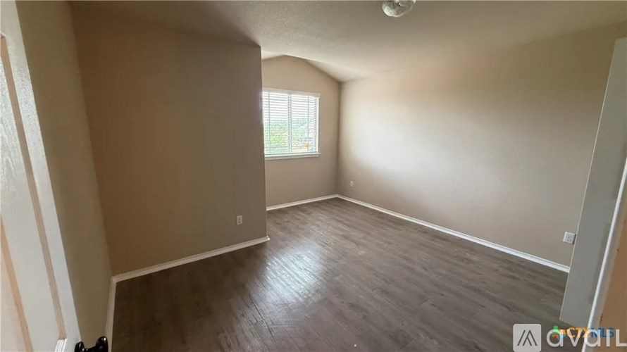 A room with wooden flooring and a window with blinds.