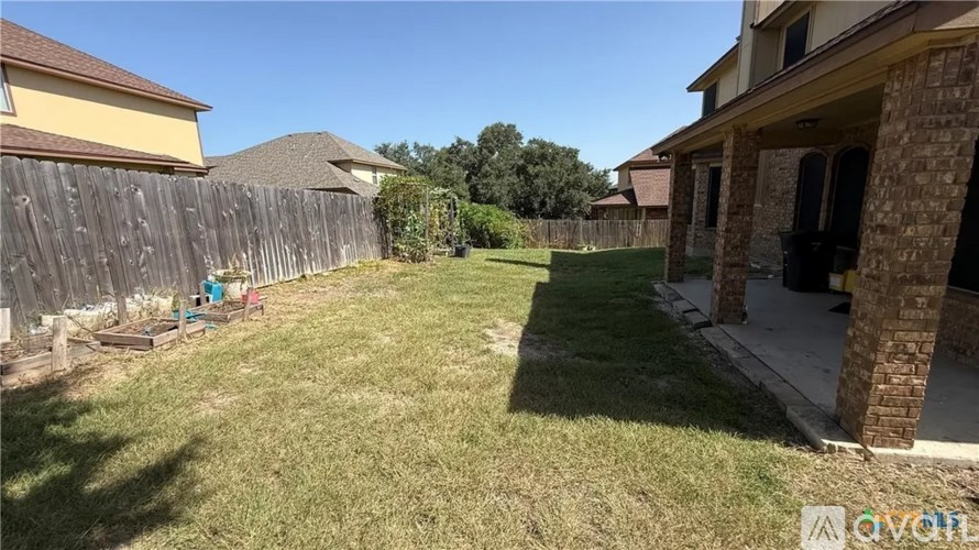 A backyard with a wooden fence and a green lawn.