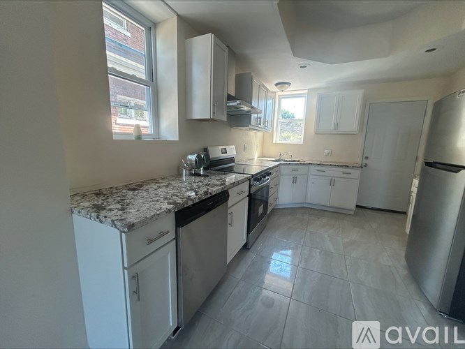 A kitchen with white cabinets and a marble countertop.