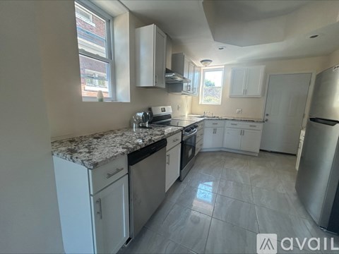 A kitchen with white cabinets and a marble countertop.