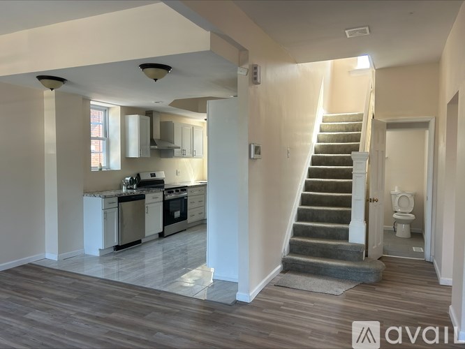 A spacious kitchen and living room with a staircase leading to the bedrooms.