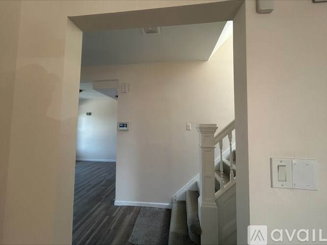 A hallway with a staircase and a light switch on the wall.