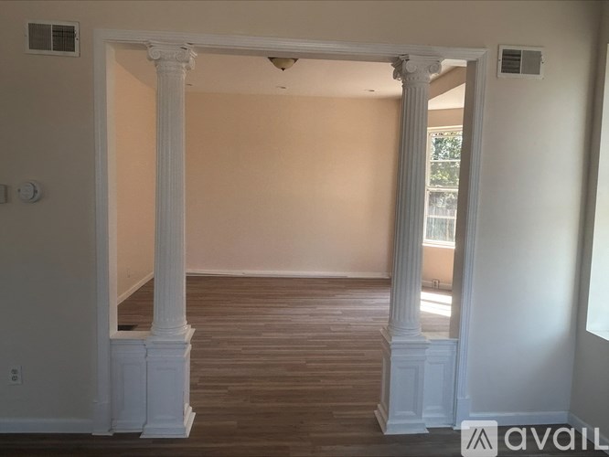 A room with white columns and wooden flooring.