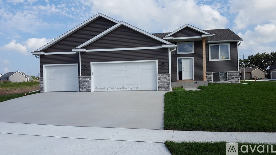 A modern house with a grey roof and two garages is for sale.