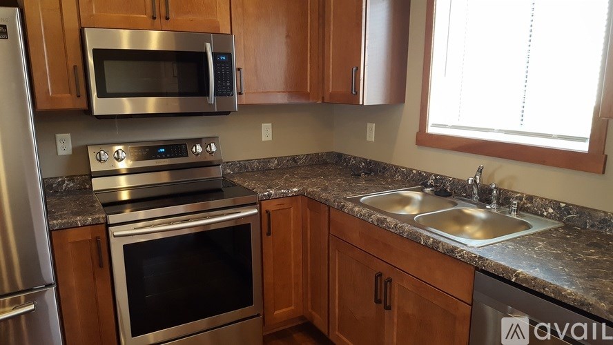 A kitchen with a stainless steel refrigerator, microwave, oven, and sinks.
