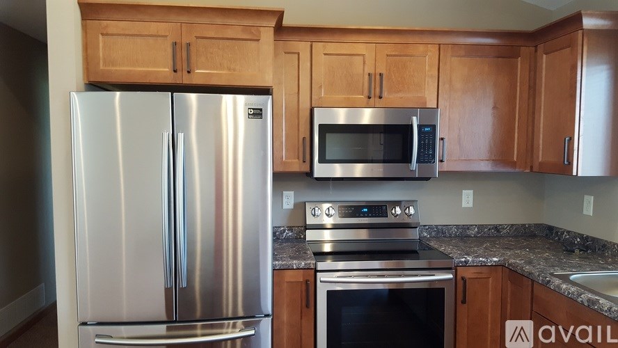 A kitchen with a stainless steel refrigerator, microwave, oven, and cabinets.