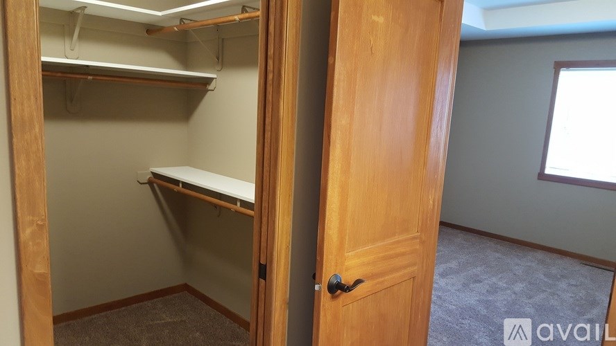 A small closet with a white shelf and a wooden door.