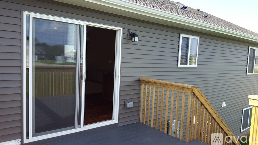 A grey house with a wooden deck and a sliding glass door.