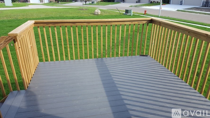 A wooden deck with a grey floor and a wooden fence.