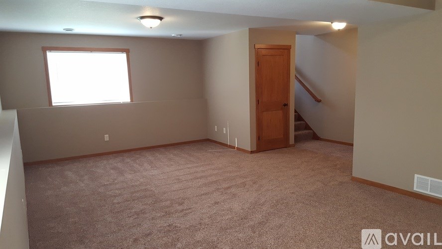 A room with a carpeted floor, a window, and a door.