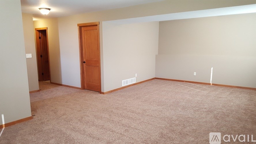 A room with a carpeted floor and two doors.