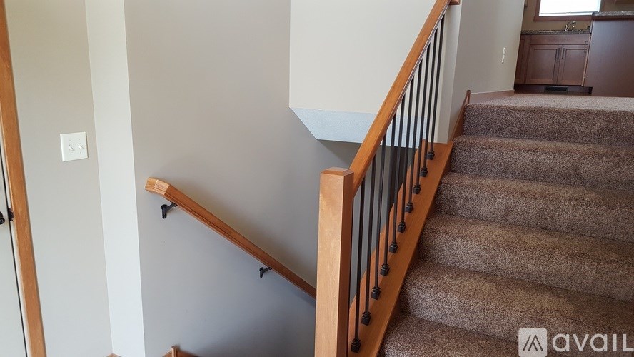 A staircase with a wooden handrail and a carpeted runner.