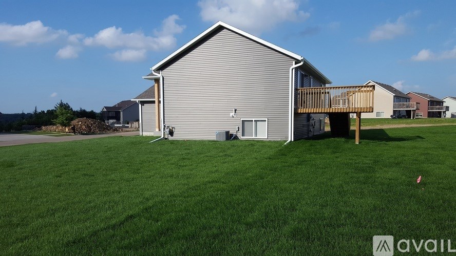 A house with a grey roof and a wooden deck is available for sale.