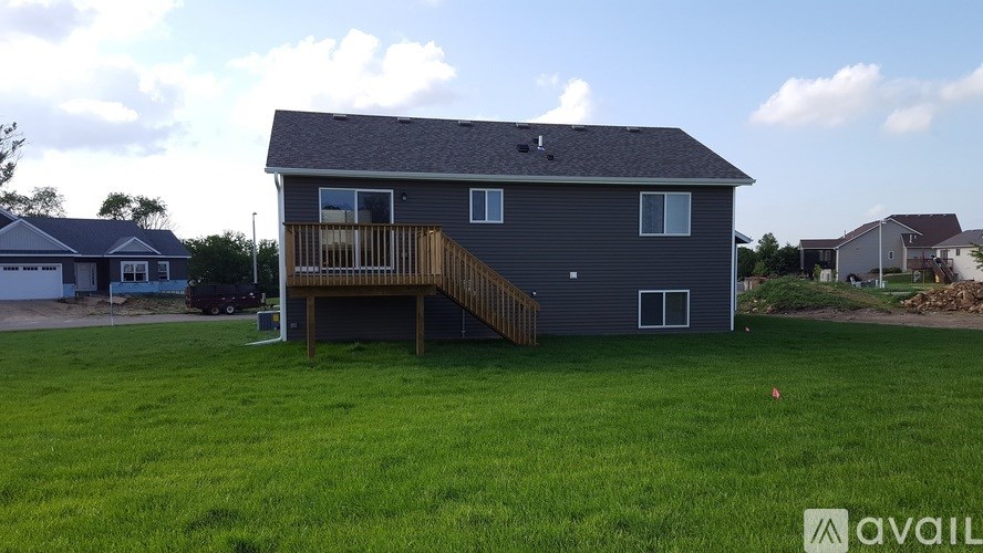 A house with a grey exterior and a wooden deck is for sale.