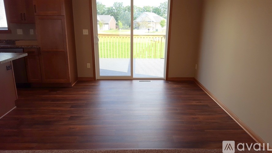 A room with wooden floors and a sliding glass door leading to a backyard.