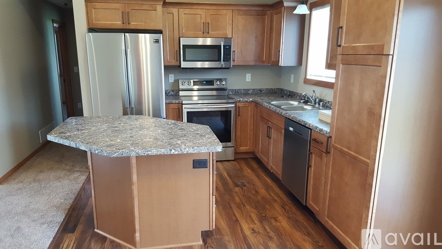 A kitchen with wooden cabinets and a granite island.