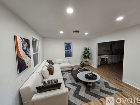 A modern living room with a white sofa, a coffee table, and a painting on the wall.