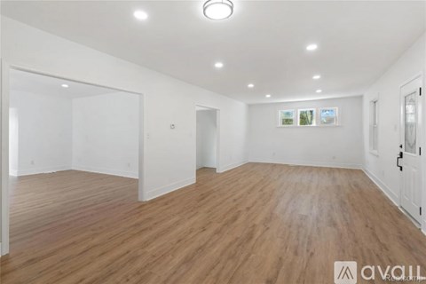 A spacious room with wooden flooring and white walls.