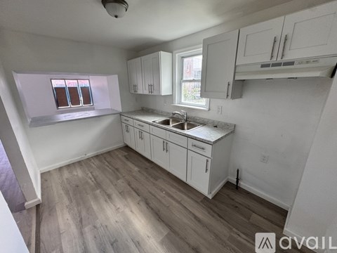 A kitchen with white cabinets and a window.