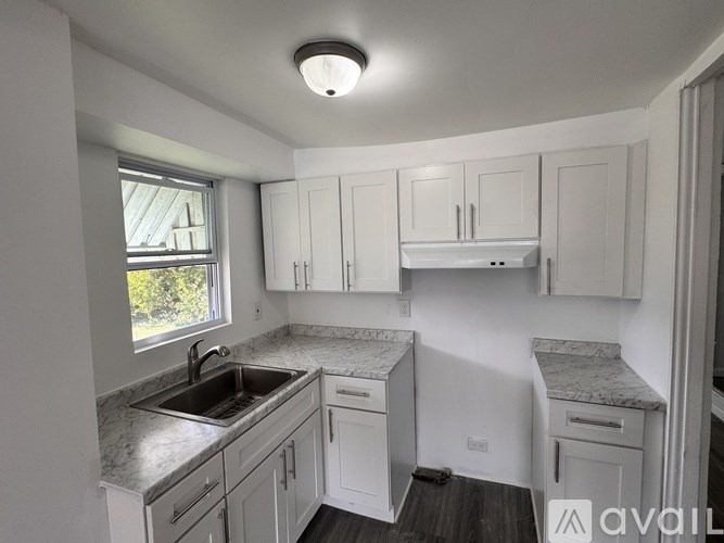 A kitchen with white cabinets and a marble countertop.