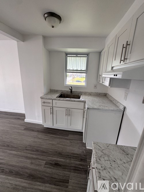 A kitchen with white cabinets and a window.