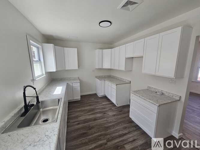 A kitchen with white cabinets and a marble countertop.