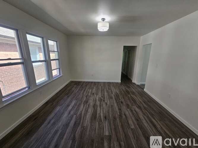 A room with wooden flooring and a window overlooking a brick building.