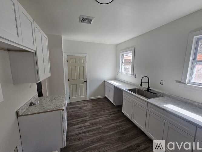 A kitchen with white cabinets and a wooden floor.