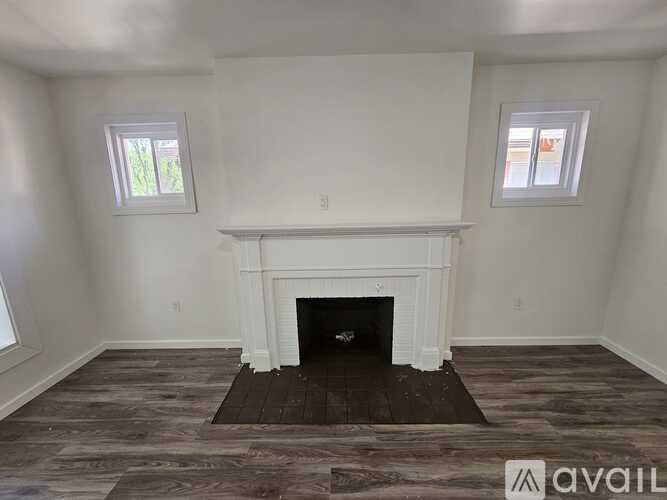 A room with a fireplace and two windows.