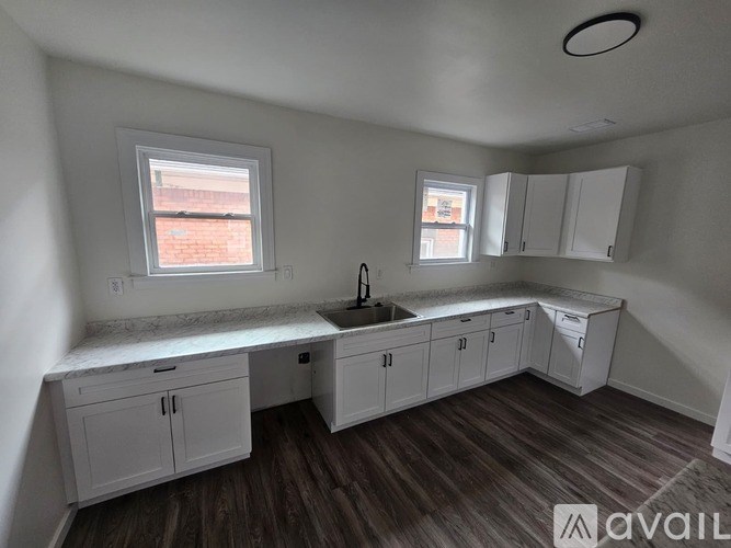 A kitchen with white cabinets and a wooden floor.