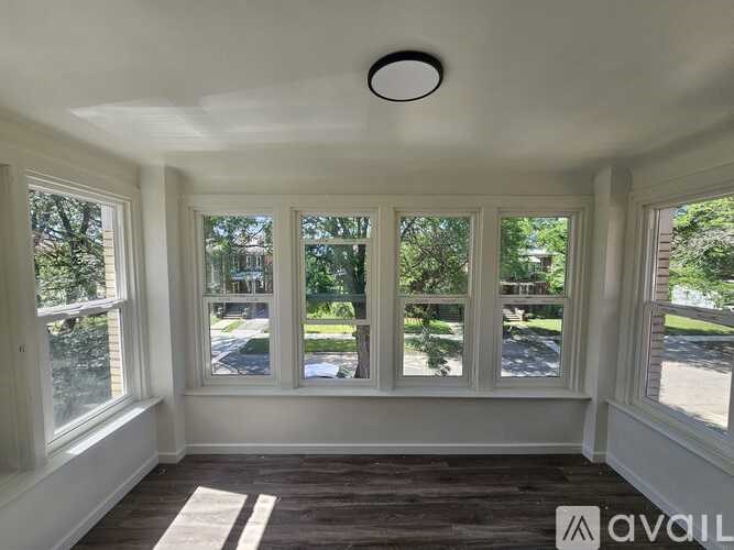 A room with a white ceiling and wooden flooring with a window overlooking a street.