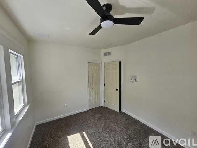 A room with a ceiling fan and two doors.