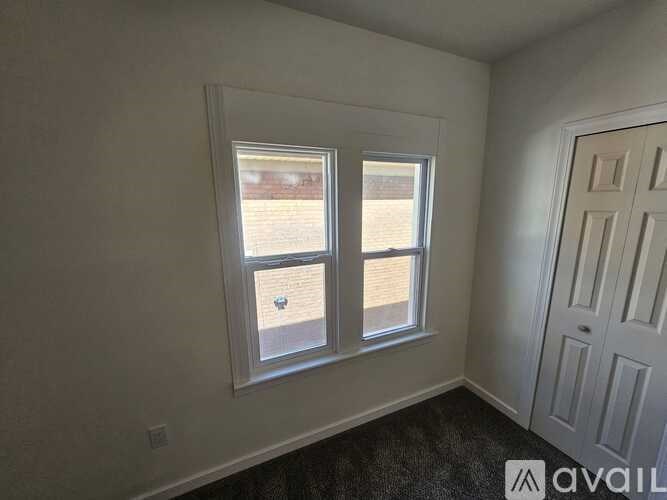 A room with two windows and a door is available for rent.
