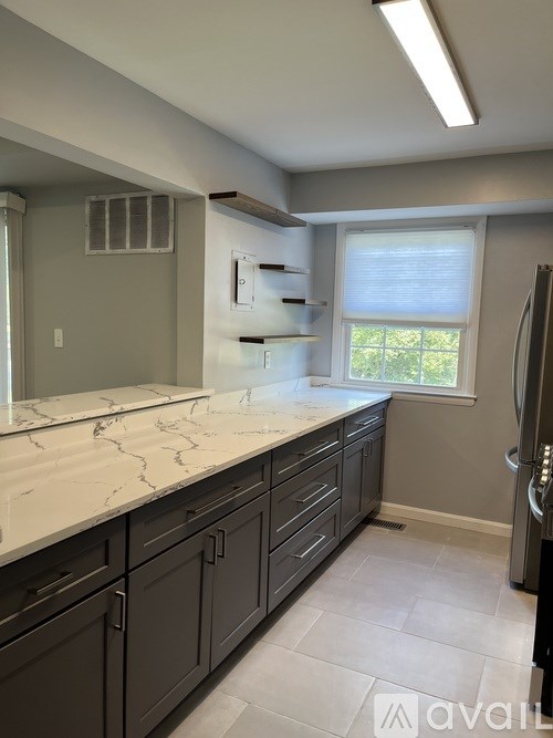 A kitchen with a marble countertop and dark cabinets.