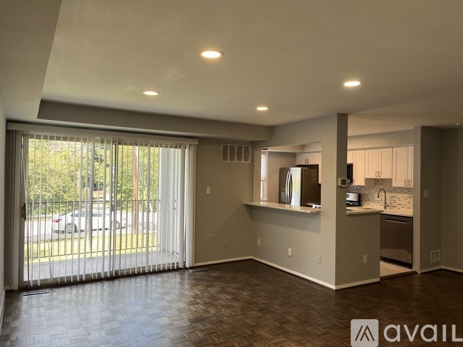 A spacious living room with a kitchen in the background.