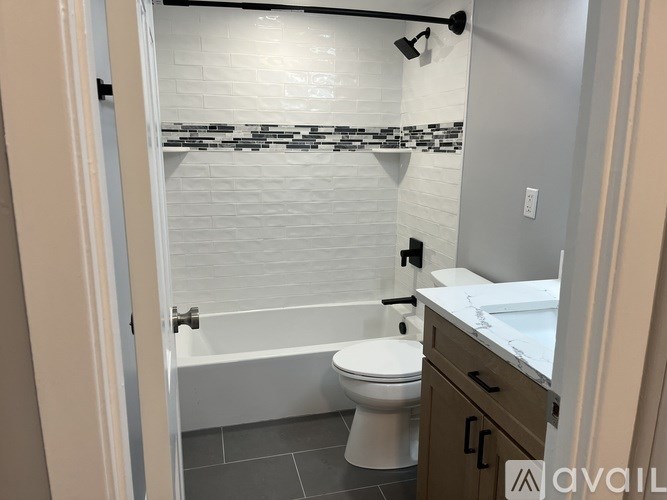 A bathroom with a white toilet and a white tiled shower.