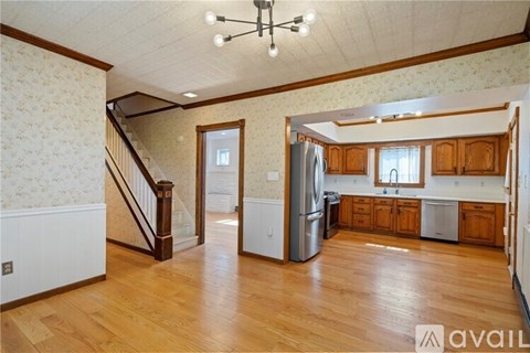 A kitchen with wooden cabinets and a refrigerator in the middle of the room.