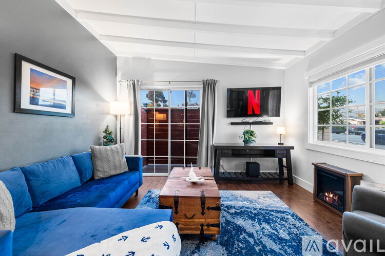 A bedroom with a large bed, a desk with a lamp, and a wardrobe with clothes hanging on it.
