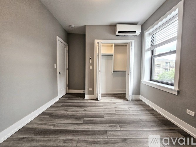 A room with a wooden floor and a window on the right side.