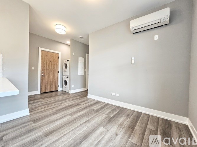 A room with a wooden floor and a white wall with a window.