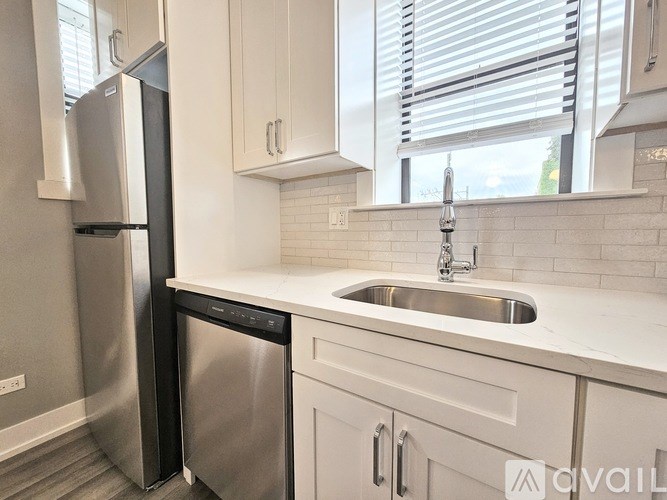 A kitchen with a stainless steel dishwasher and a white countertop.