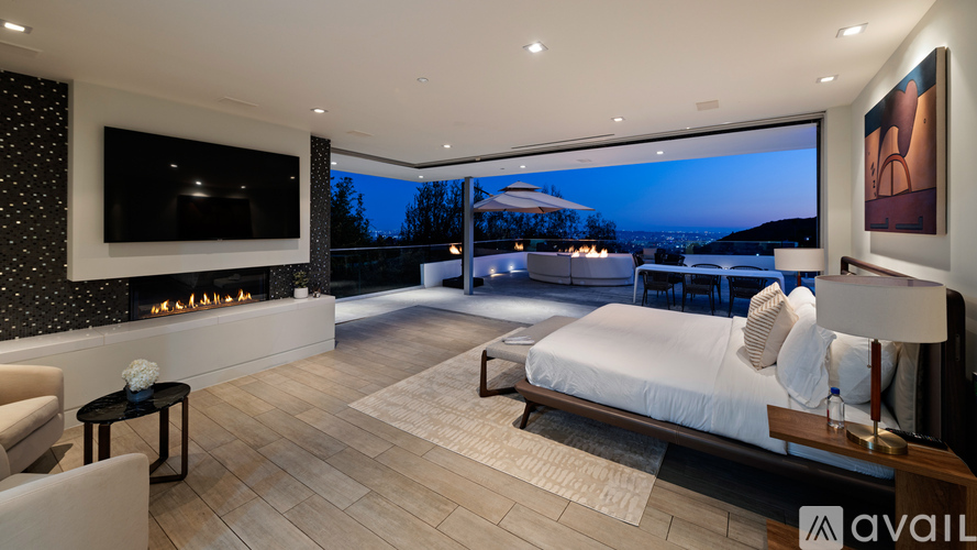 A modern bedroom with a large bed and a fireplace.