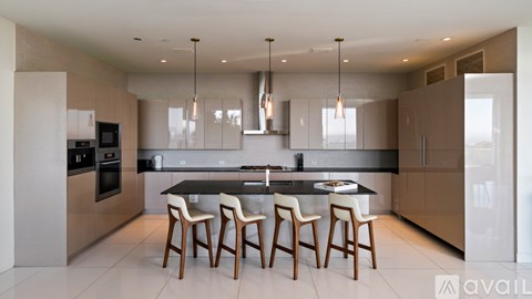 A modern kitchen with a black countertop and wooden chairs.
