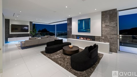 A modern living room with a large black couch and a coffee table in the center.