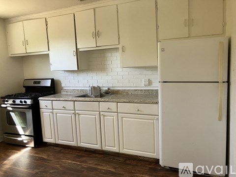 A kitchen with white cabinets and a white refrigerator.